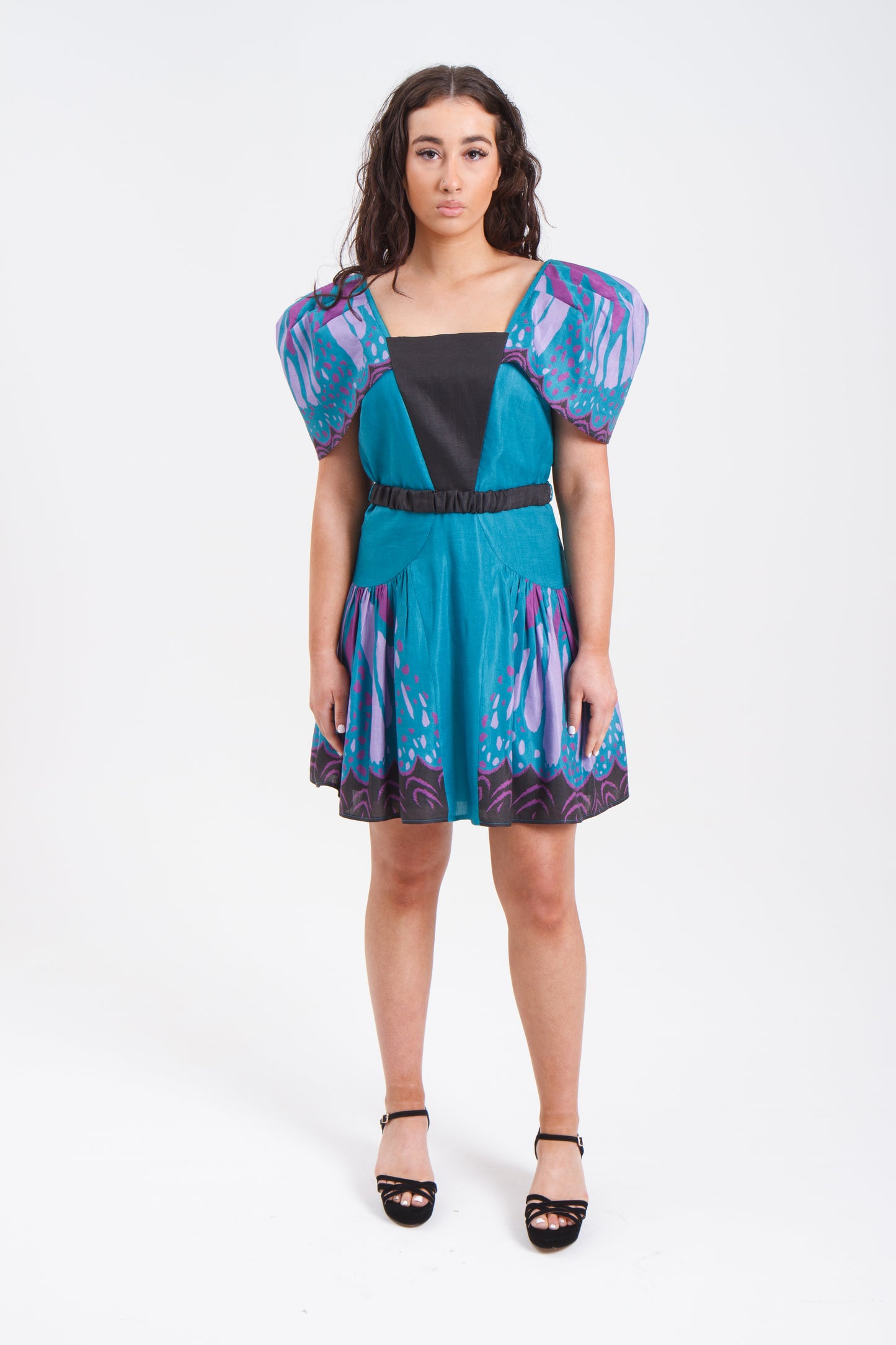 PRODUCT DESCRIPTION Premium silk cotton linen, unique square neck mini dress with voluminous sleeves, exclusive to MAZASHIE. Vibrant Placement print on sleeves and on the voluminous skirt. Voluminous sleeves add a luxurious look to the dress. Contrast front yoke. The elasticated contrast waist belt makes a perfect fit. Invisible back zip closure. Shoulder retainers at each side of the shoulder to snaped through the bra straps to keep the dress in place. Fully lined in soft cotton.