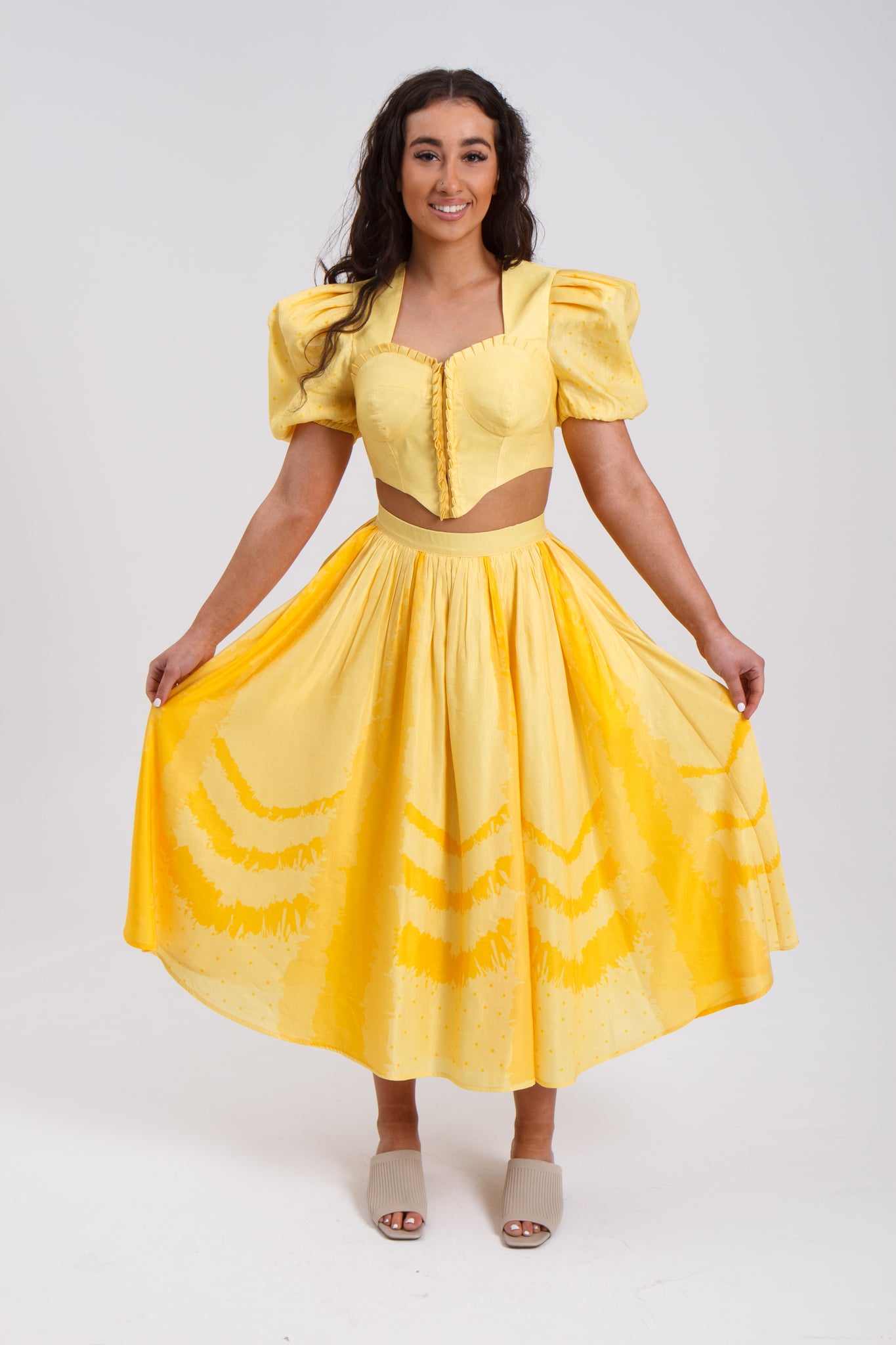 PRODUCT DESCRIPTION Premium silk cotton linen, Daffodil-Yellow unique 2-piece midi dress with short puff sleeves exclusive to MAZASHIE. Sweetheart neck, crop top with shirred back and bra-cut detail. Placement prints on the voluminous skirt and polka-dotted puff sleeves. The elasticated skirt waistband makes a perfect fit. The shirred back band makes a perfect fit. Invisible back zip closure at skirt. Side seam concealed pockets. Hooks and eyes closure at front.