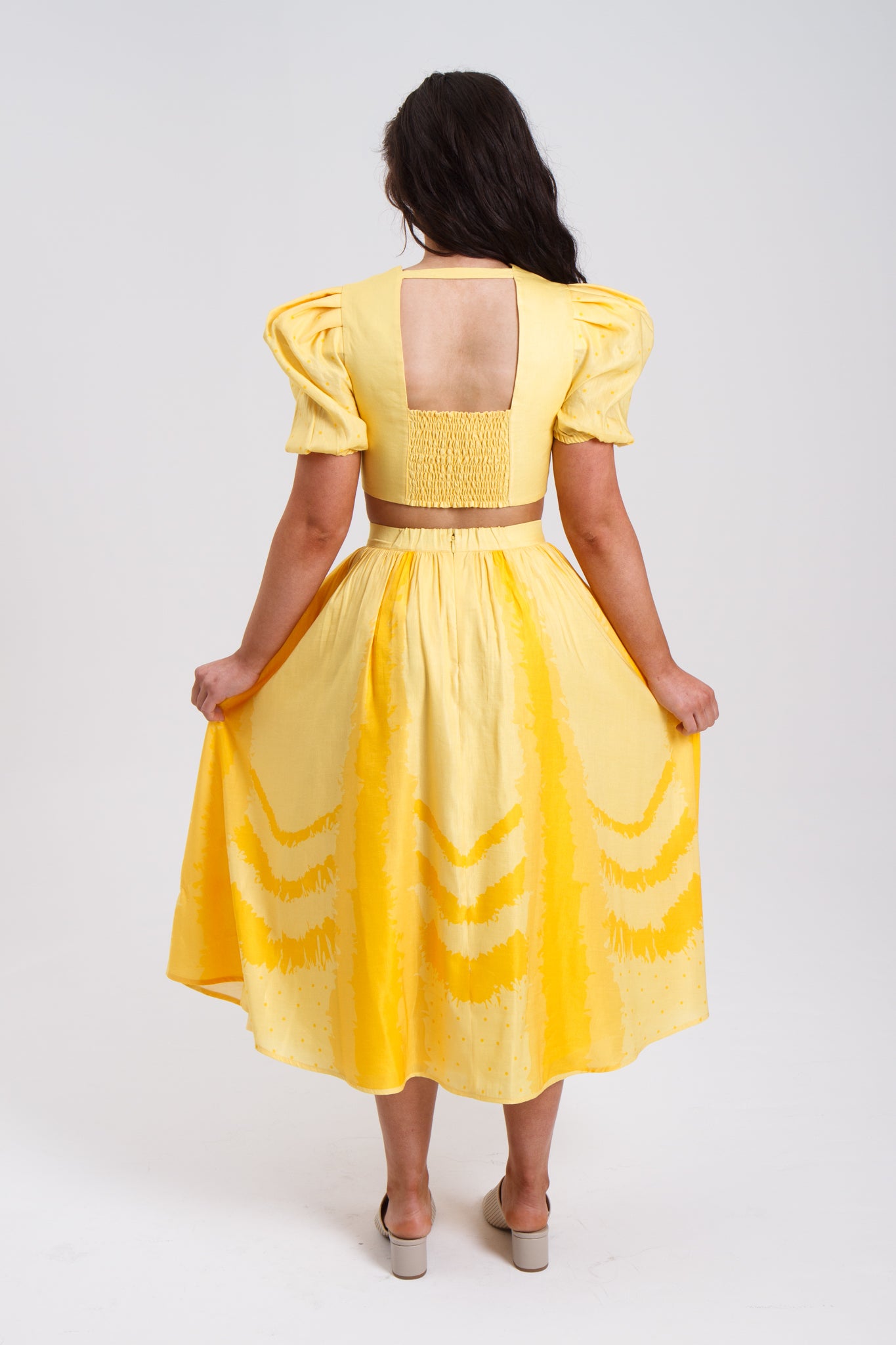 PRODUCT DESCRIPTION Premium silk cotton linen, Daffodil-Yellow unique 2-piece midi dress with short puff sleeves exclusive to MAZASHIE. Sweetheart neck, crop top with shirred back and bra-cut detail. Placement prints on the voluminous skirt and polka-dotted puff sleeves. The elasticated skirt waistband makes a perfect fit. The shirred back band makes a perfect fit. Invisible back zip closure at skirt. Side seam concealed pockets. Hooks and eyes closure at front.