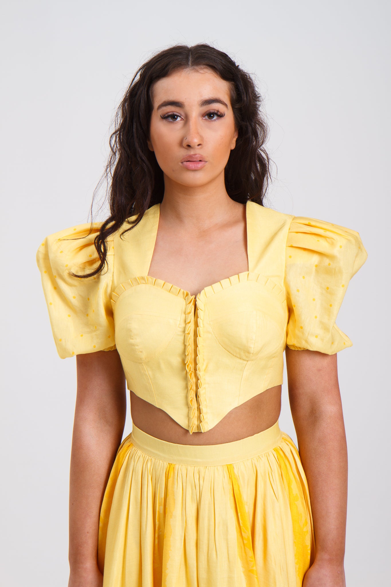 PRODUCT DESCRIPTION Premium silk cotton linen, Daffodil-Yellow unique 2-piece midi dress with short puff sleeves exclusive to MAZASHIE. Sweetheart neck, crop top with shirred back and bra-cut detail. Placement prints on the voluminous skirt and polka-dotted puff sleeves. The elasticated skirt waistband makes a perfect fit. The shirred back band makes a perfect fit. Invisible back zip closure at skirt. Side seam concealed pockets. Hooks and eyes closure at front.