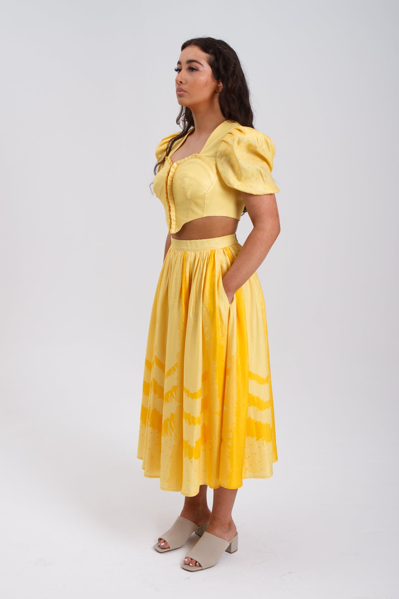PRODUCT DESCRIPTION   Premium silk cotton linen, Daffodil-Yellow unique 2-piece midi dress with short puff sleeves exclusive to MAZASHIE.  Sweetheart neck, crop top with shirred back and bra-cut detail.  Placement prints on the voluminous skirt and polka-dotted puff sleeves.  The elasticated skirt waistband makes a perfect fit.  The shirred back band makes a perfect fit.  Invisible back zip closure at skirt.  Side seam concealed pockets.  Hooks and eyes closure at front.