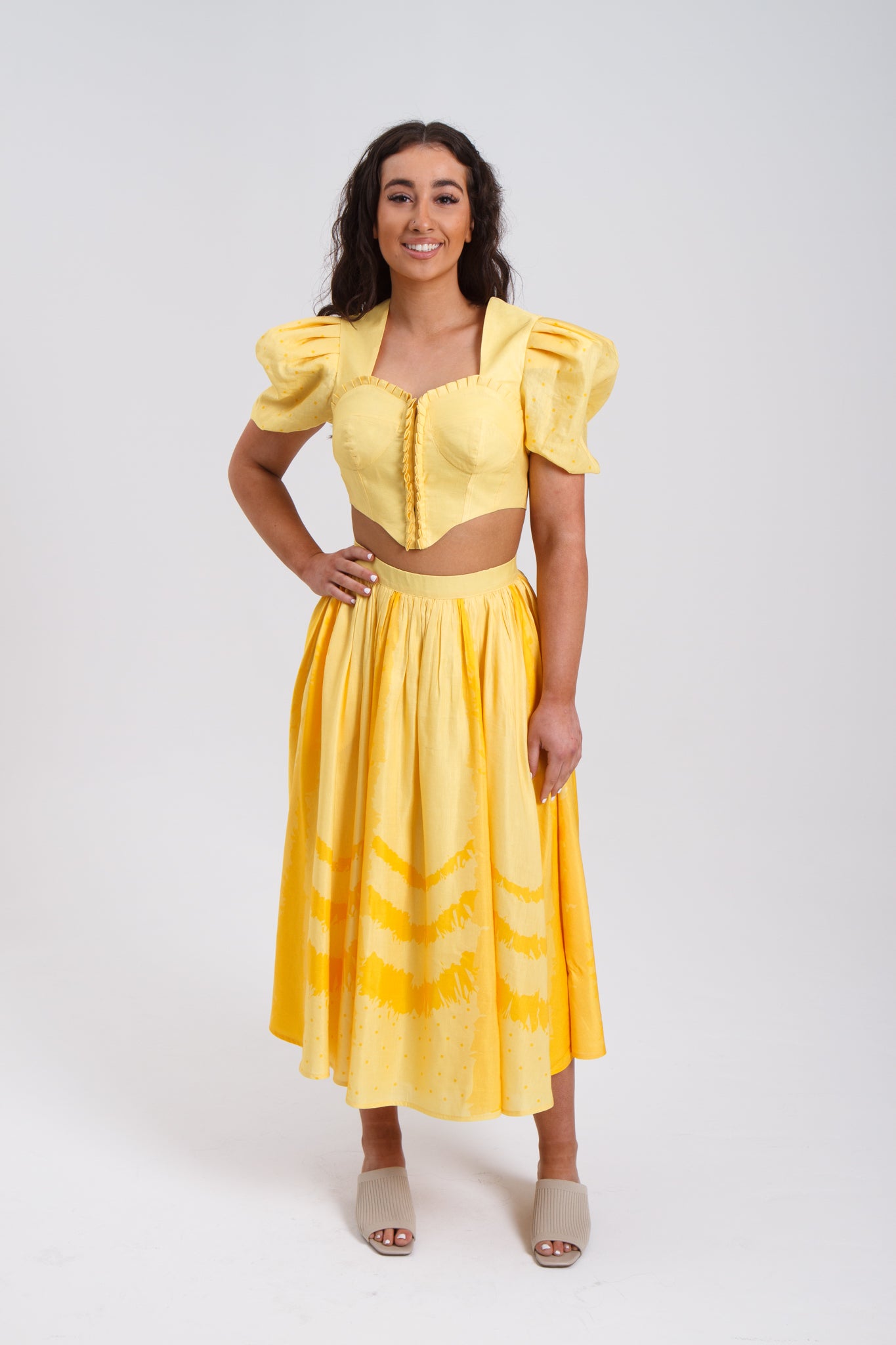 PRODUCT DESCRIPTION   Premium silk cotton linen, Daffodil-Yellow unique 2-piece midi dress with short puff sleeves exclusive to MAZASHIE.  Sweetheart neck, crop top with shirred back and bra-cut detail.  Placement prints on the voluminous skirt and polka-dotted puff sleeves.  The elasticated skirt waistband makes a perfect fit.  The shirred back band makes a perfect fit.  Invisible back zip closure at skirt.  Side seam concealed pockets.  Hooks and eyes closure at front.